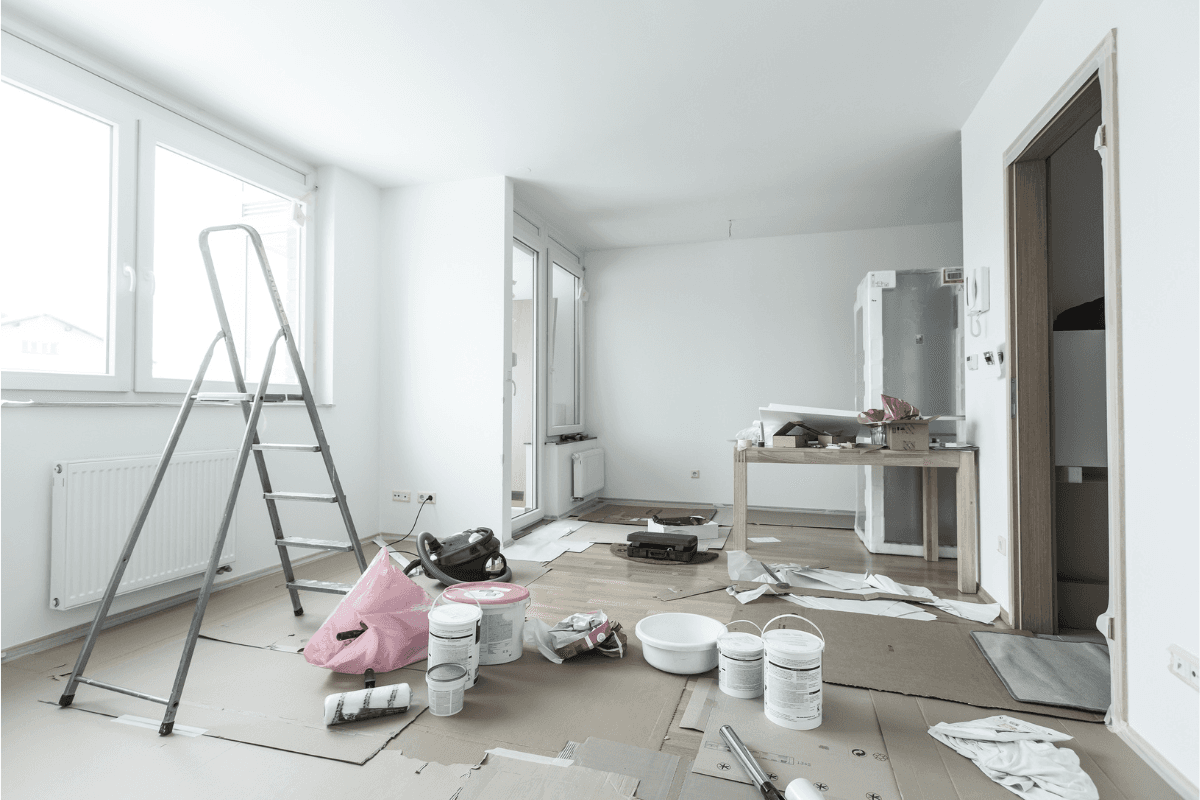 Habitación en proceso de pintura en Madrid con escalera, botes de pintura y rodillos profesionales