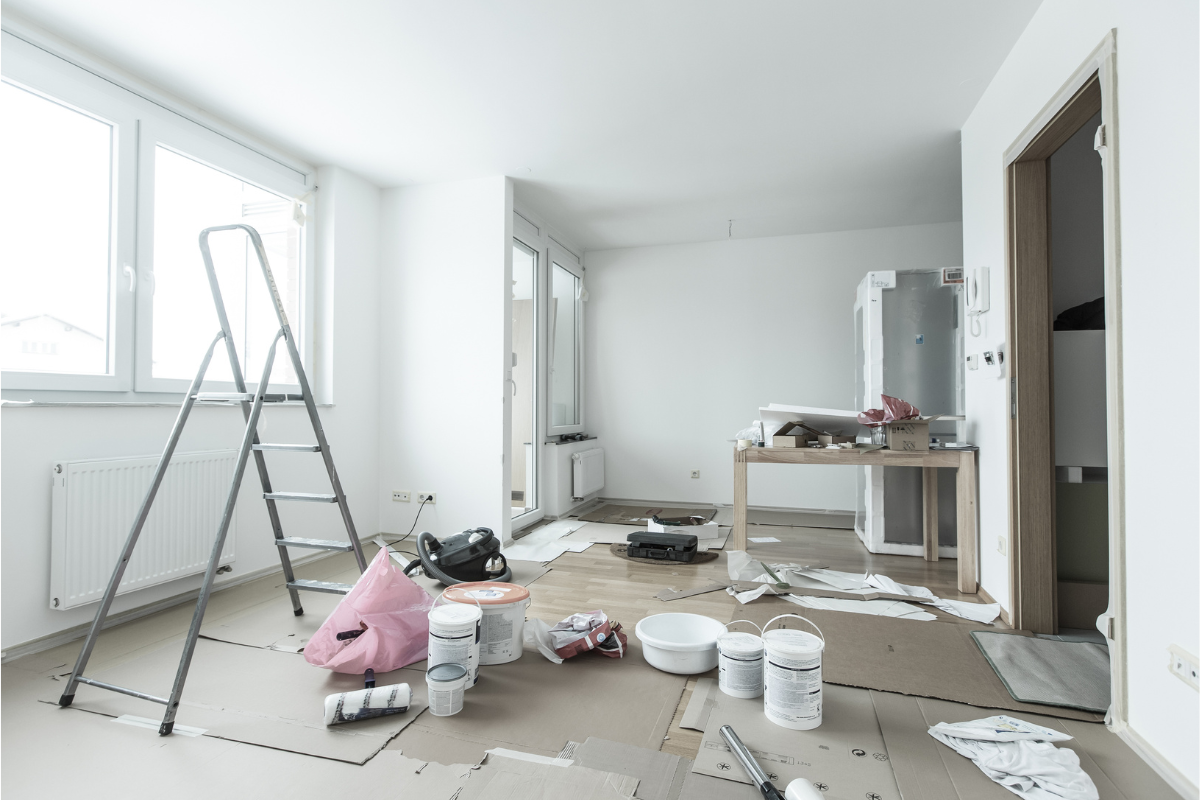 Habitación en proceso de pintura en Madrid con escalera, botes de pintura y rodillos profesionales
